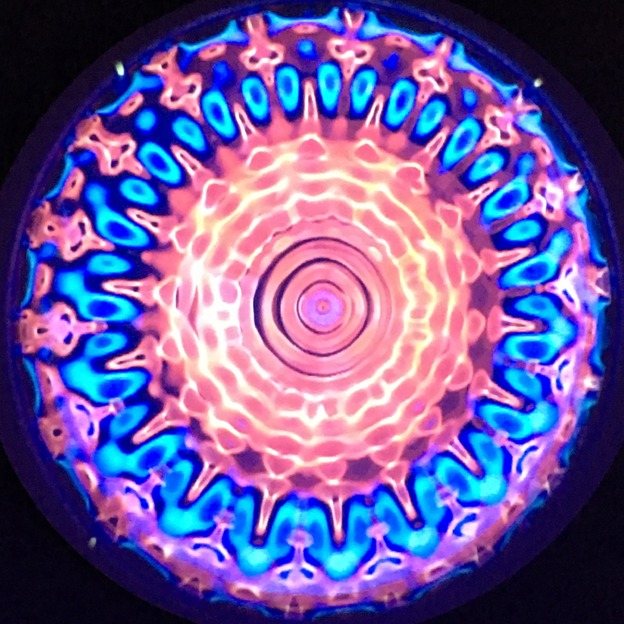 A center like a bright yellow-orange sun with spokes radiating into aqua blue waves
